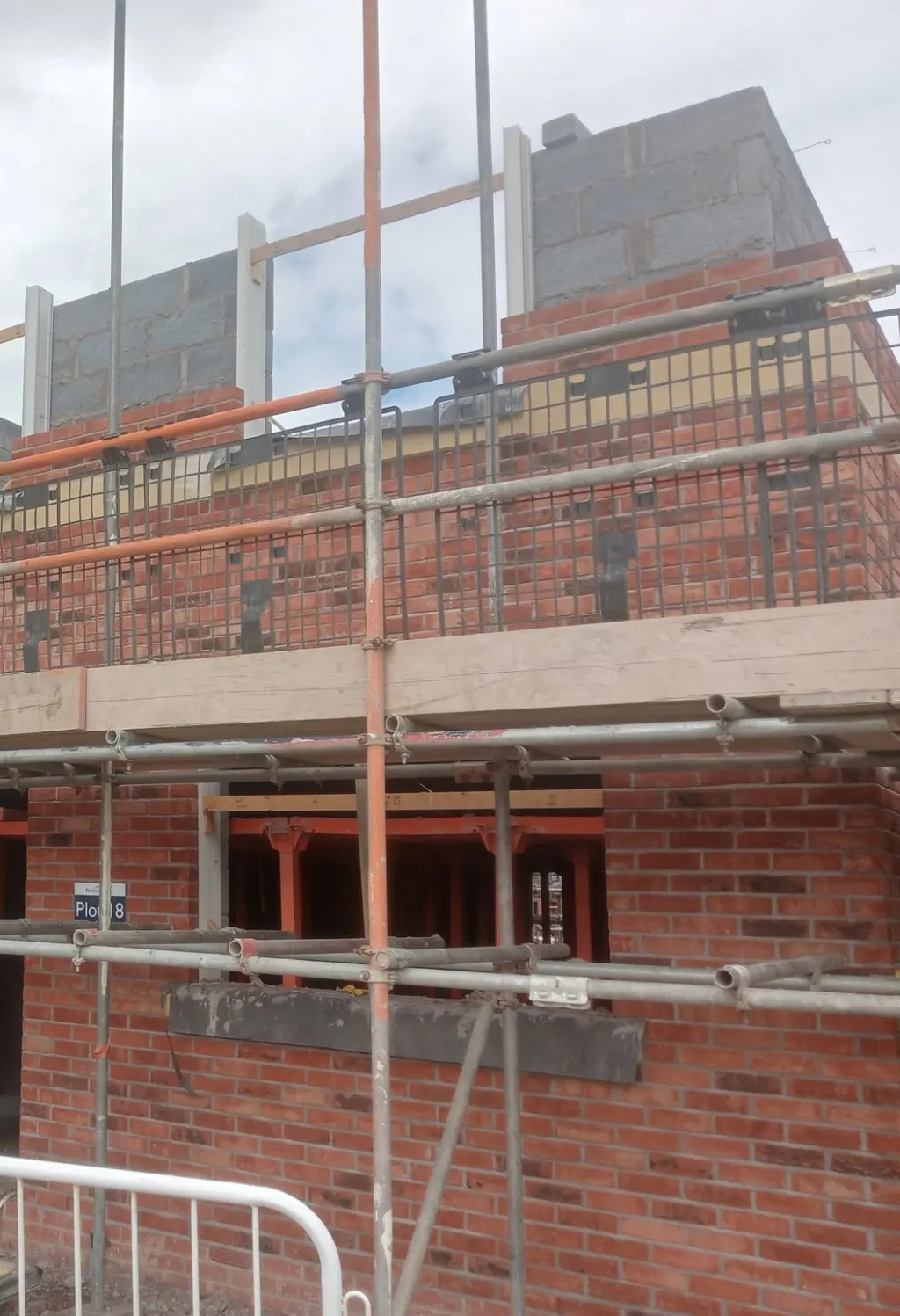 Facing brick and blockwork rising at first floor behind scaffold, with steel props in the ground-floor openings